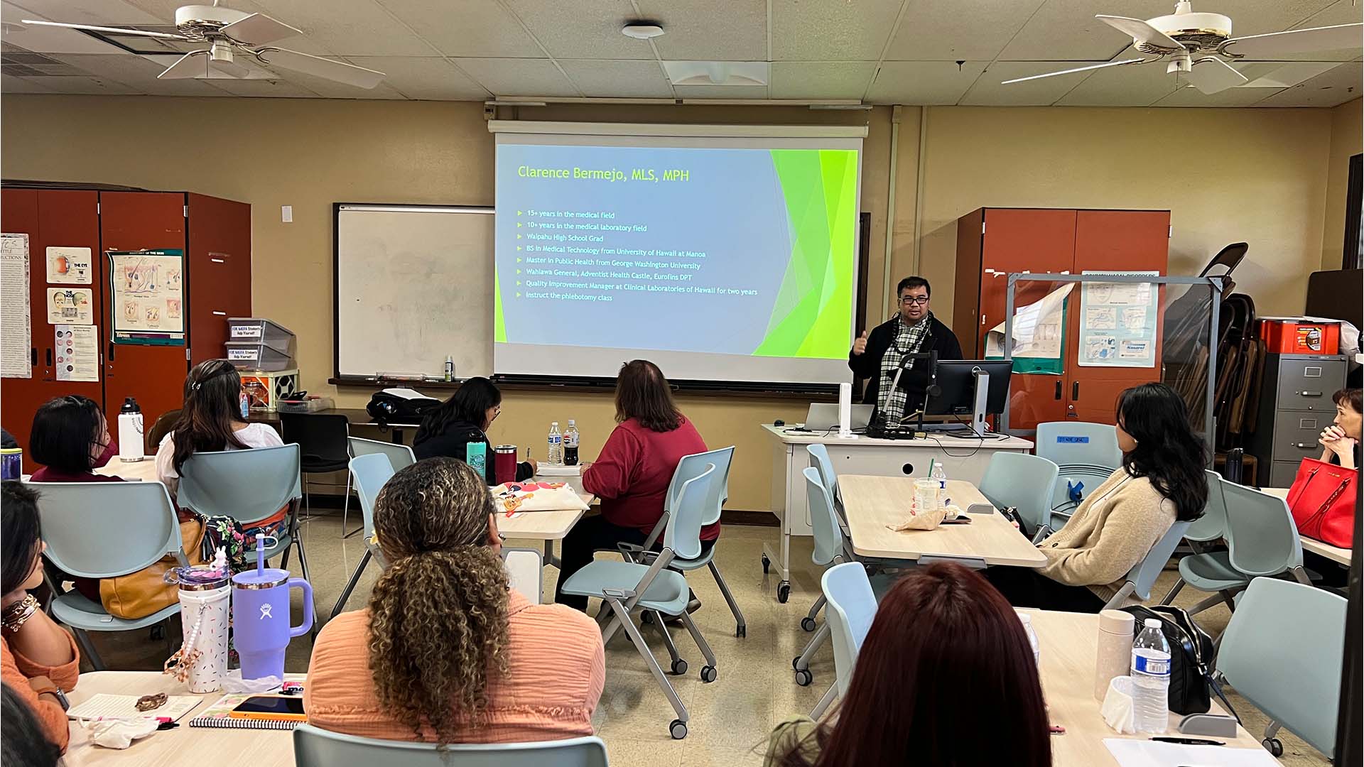 A speaker presenting on preventing specimen errors to an audience, with a slide projected on the screen and participants seated at tables.